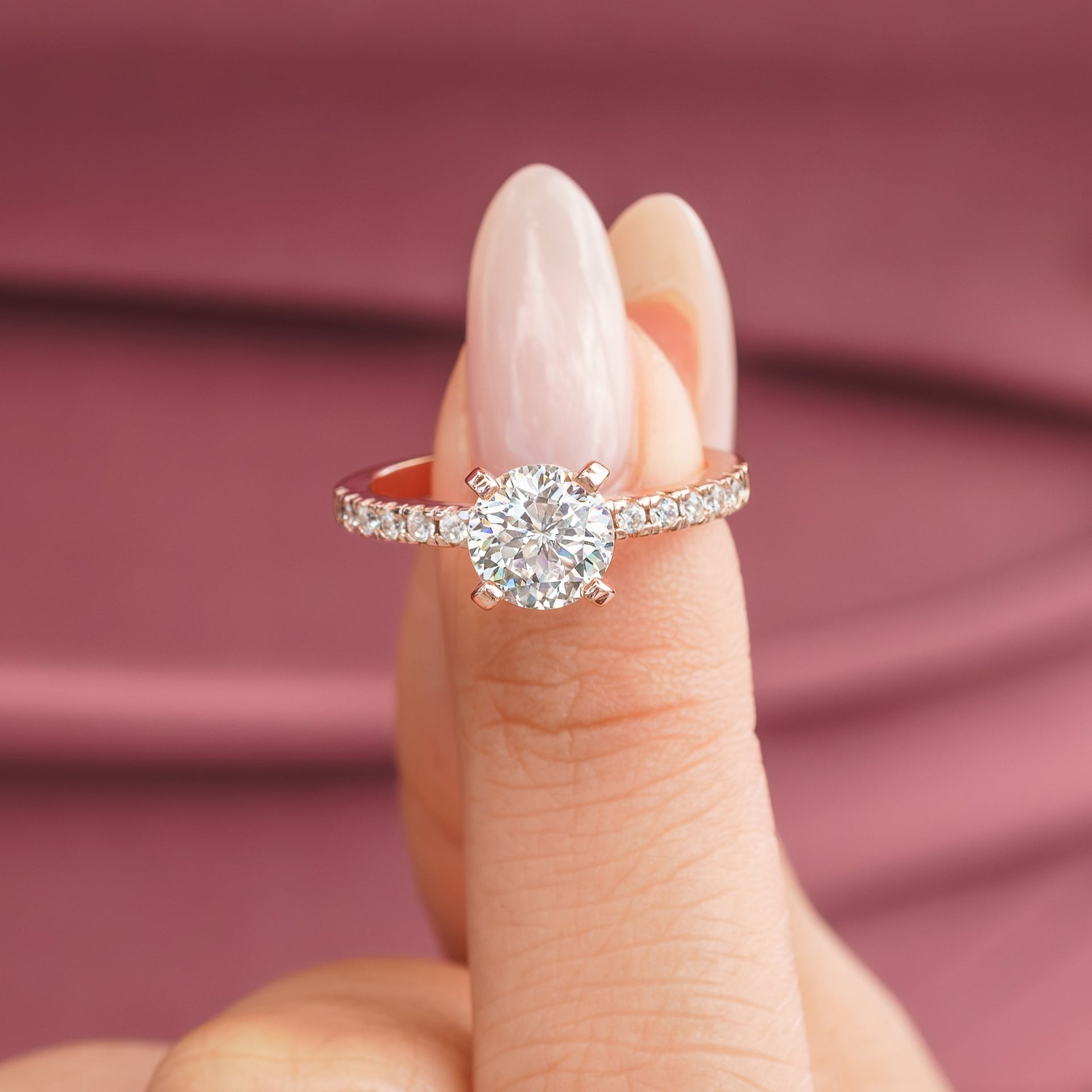 woman pinching rose gold round cut engagement ring