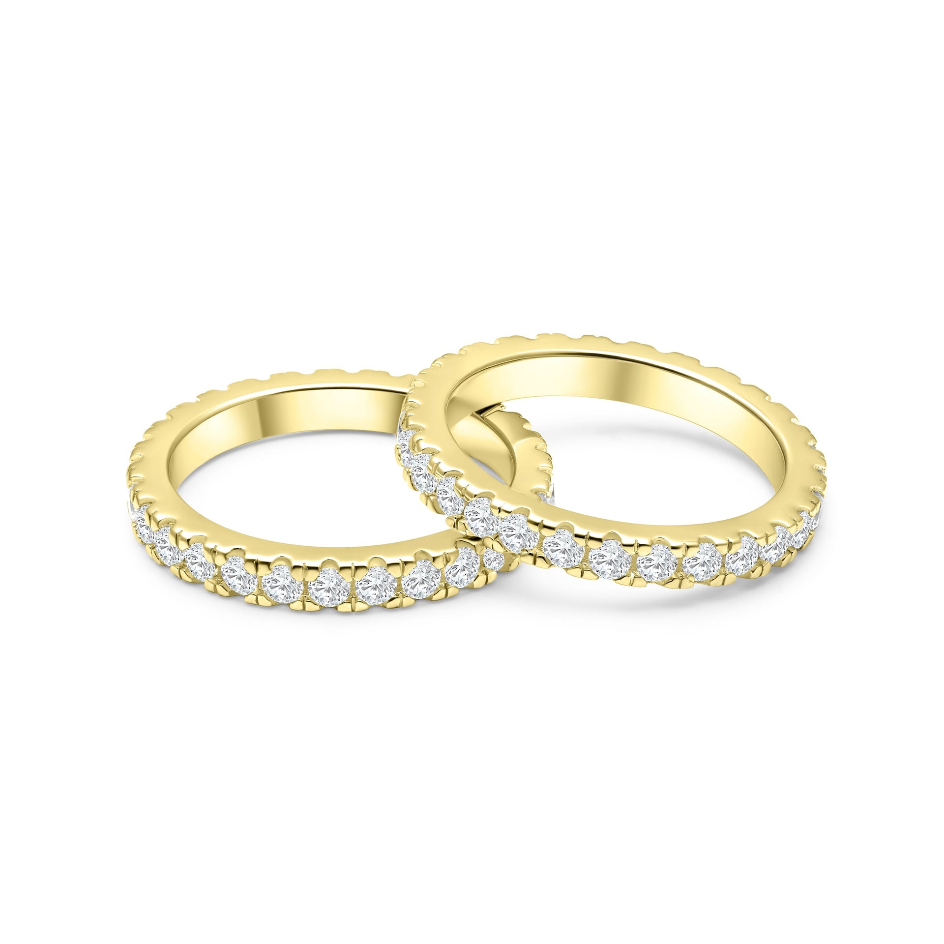 top view of two gold eternity wedding bands, with one band slightly resting atop of the other