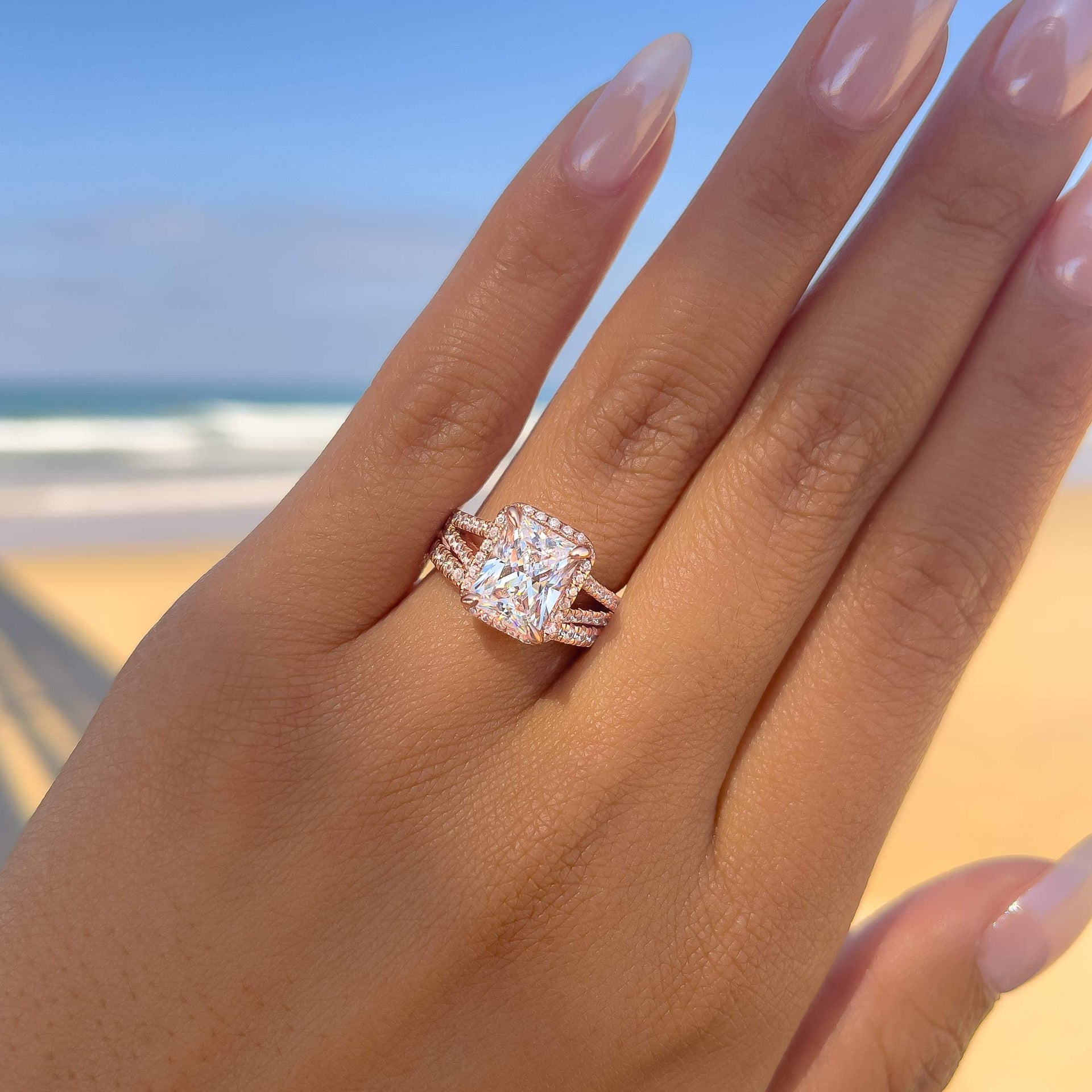 classic rose gold wedding ring set with 3.5 carat radiant cut center stone on female model with ocean in background