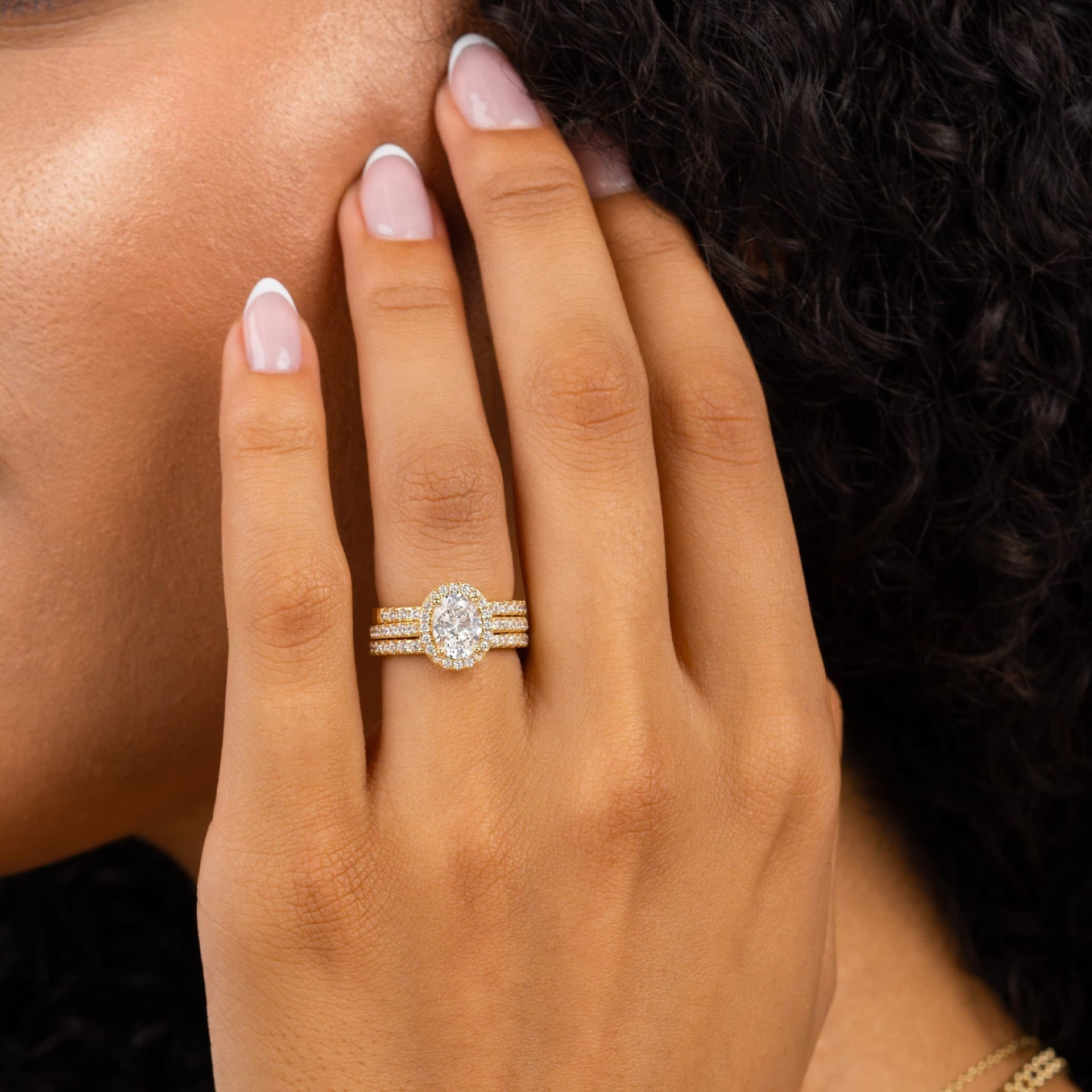 woman wearing gold promise band with halo engagement ring
