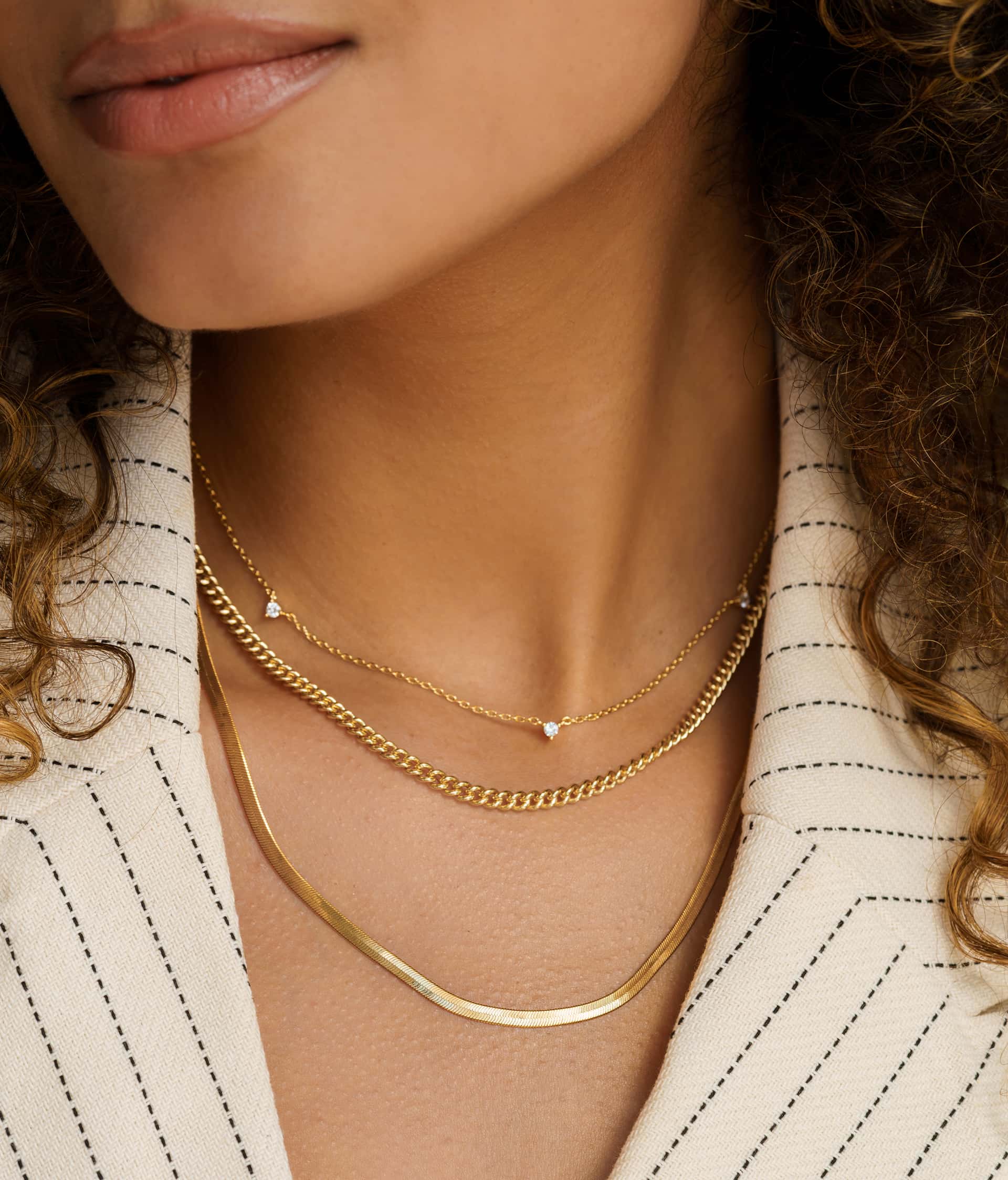 woman wearing three gorgeous gold necklaces to create a necklace stack accessories