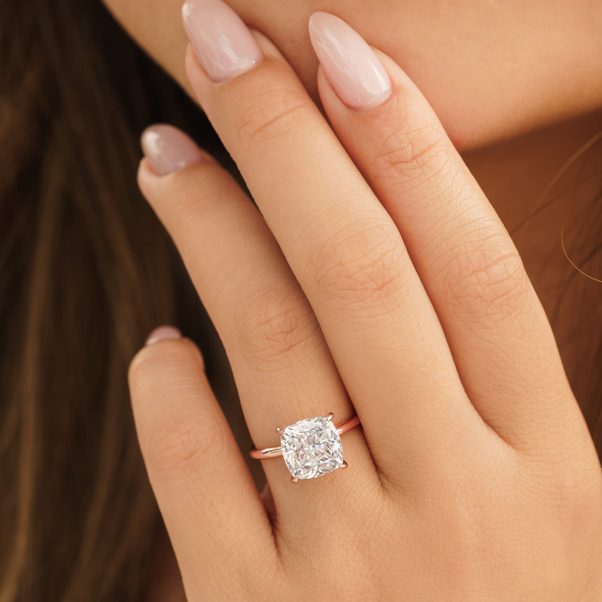 woman wearing rose gold cushion cut engagement ring on hand