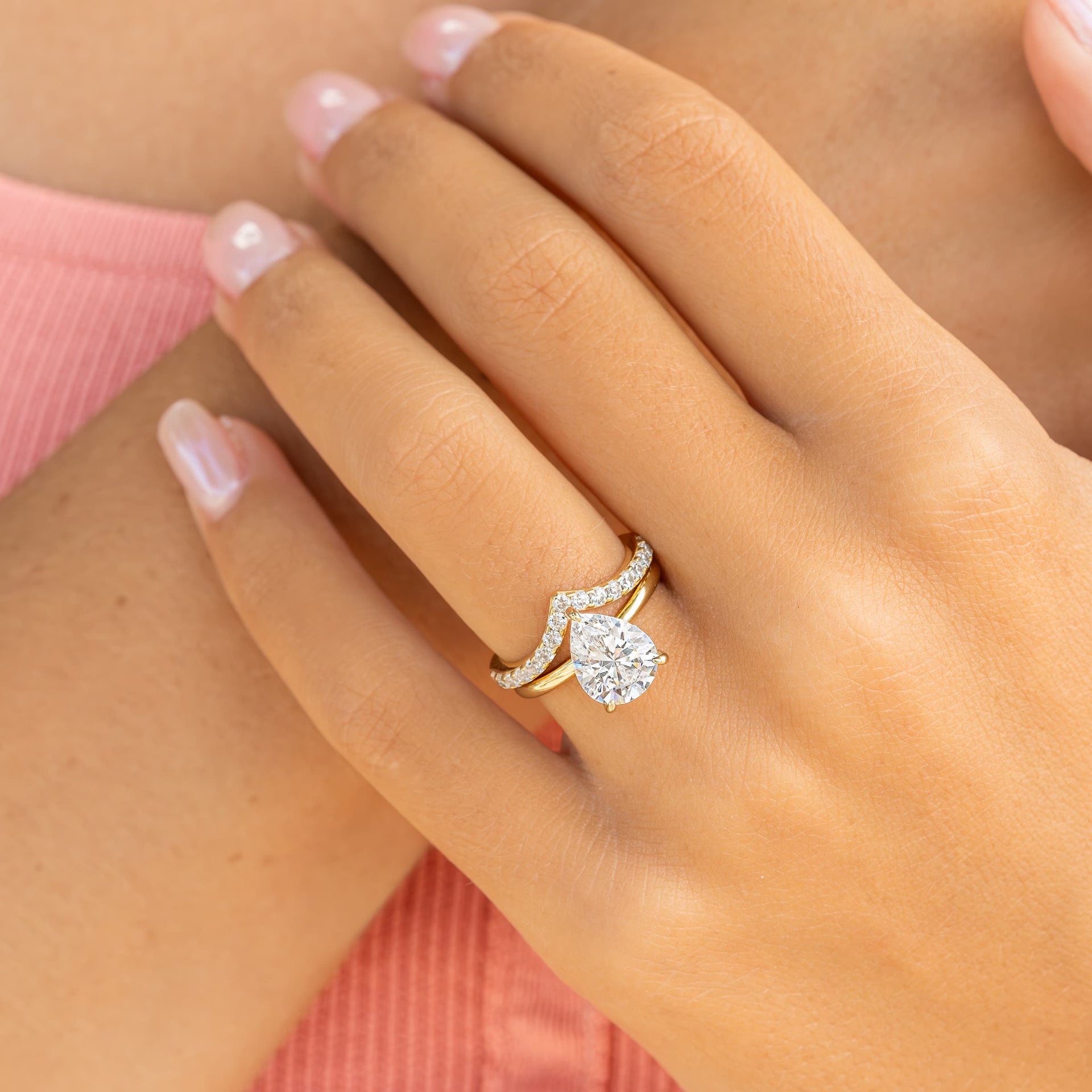 woman wearing v shaped wedding band with pear shaped gold engagement ring