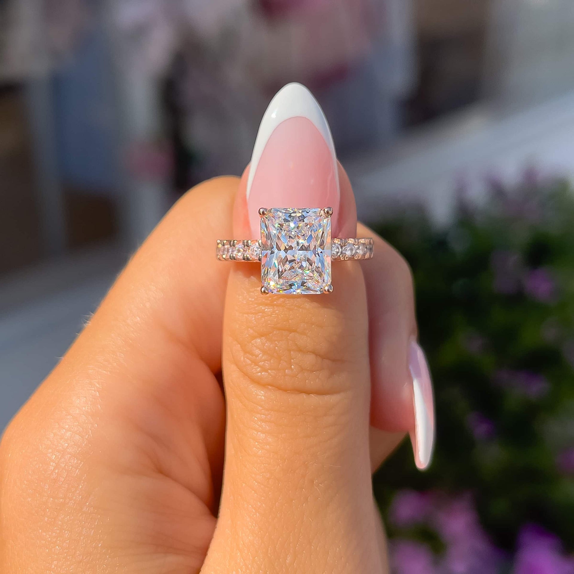 gorgeous rose gold radiant cut engagement ring on ladies thumb with french trip