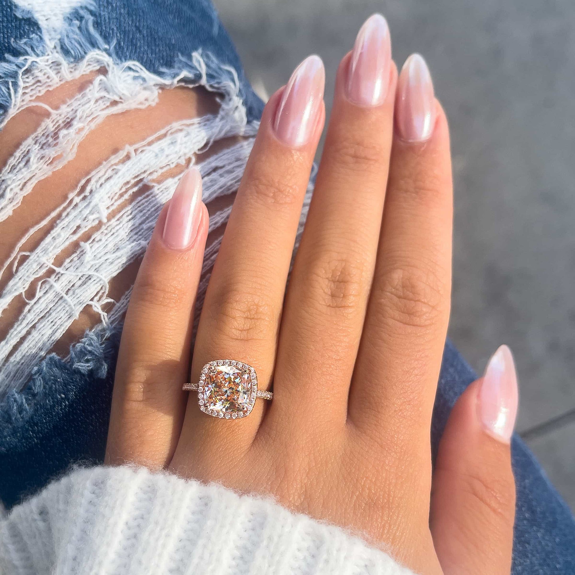 lovely rose gold cushion cut engagement ring on ladies hand with jeans