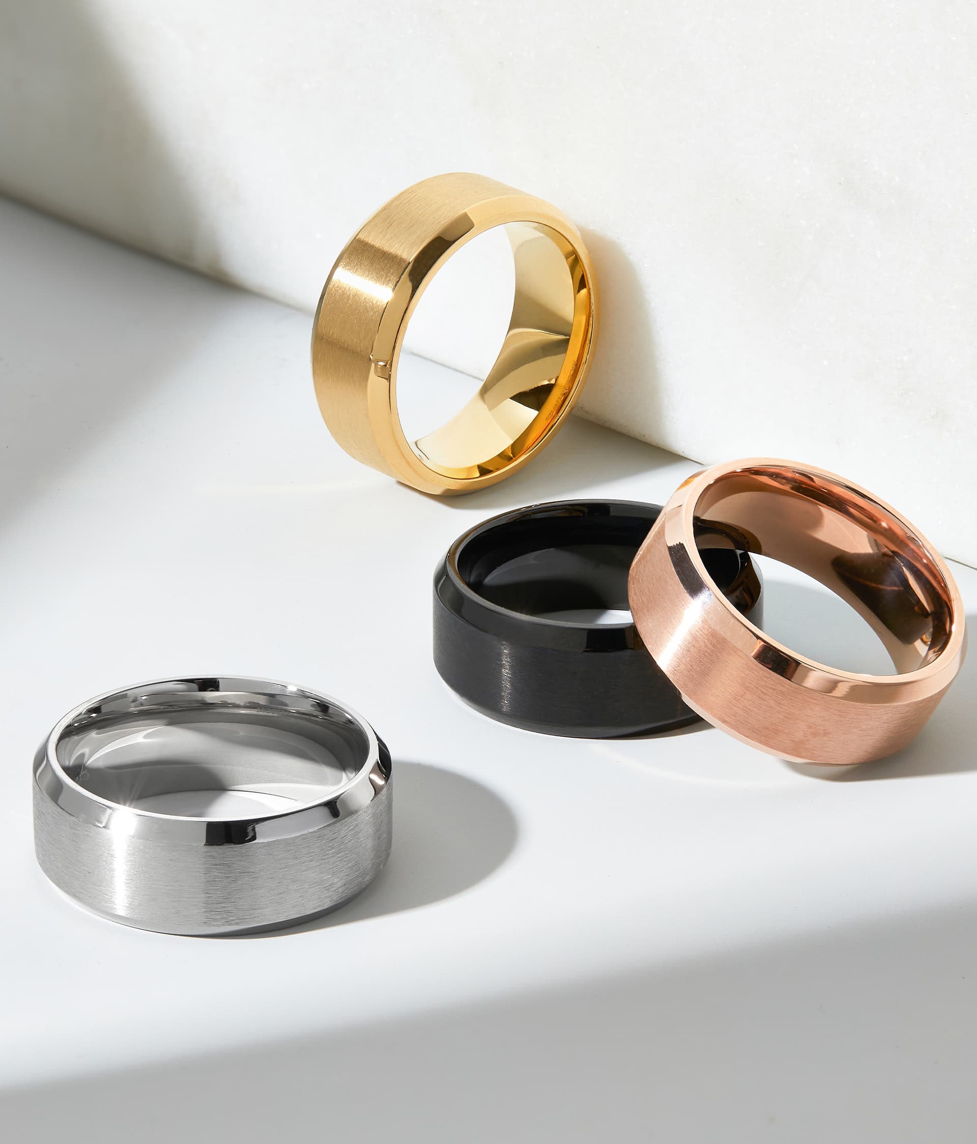 flatlay of men's bands together in silver, black, gold, and rose gold