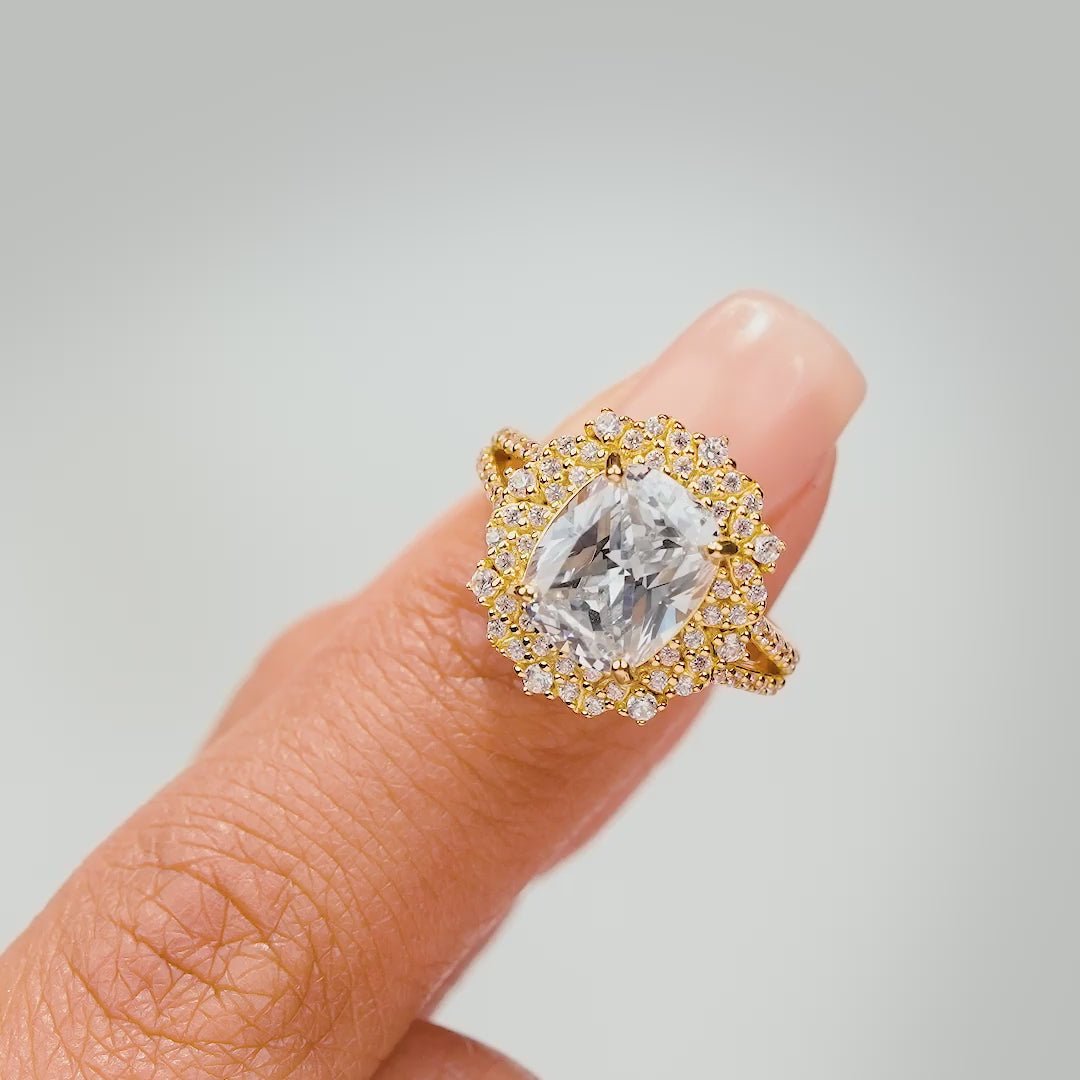 Video of the Sol featuring a stunning 2.5 carat elongated cushion cut center stone surrounded by smaller, intricate gems shown in gold.