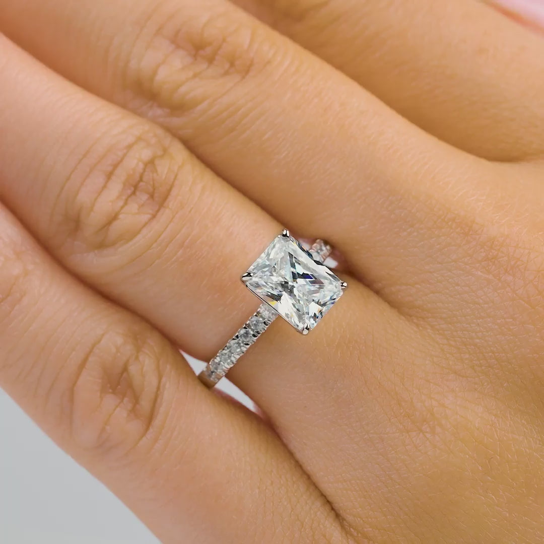 Multi-view video of stunning silver radiant cut engagement ring with a half eternity band, being shown by model with light pink nails