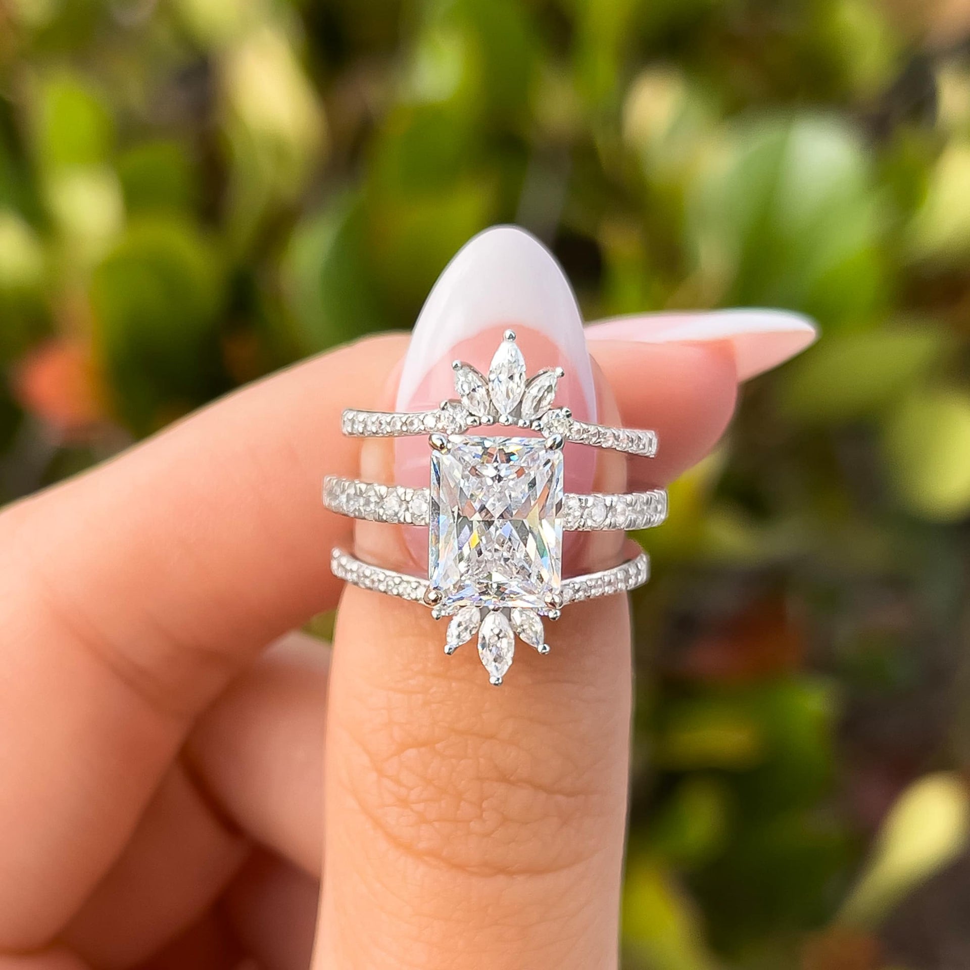 silver radiant cut engagement ring paired with two boho bands on female hand with french tip nails