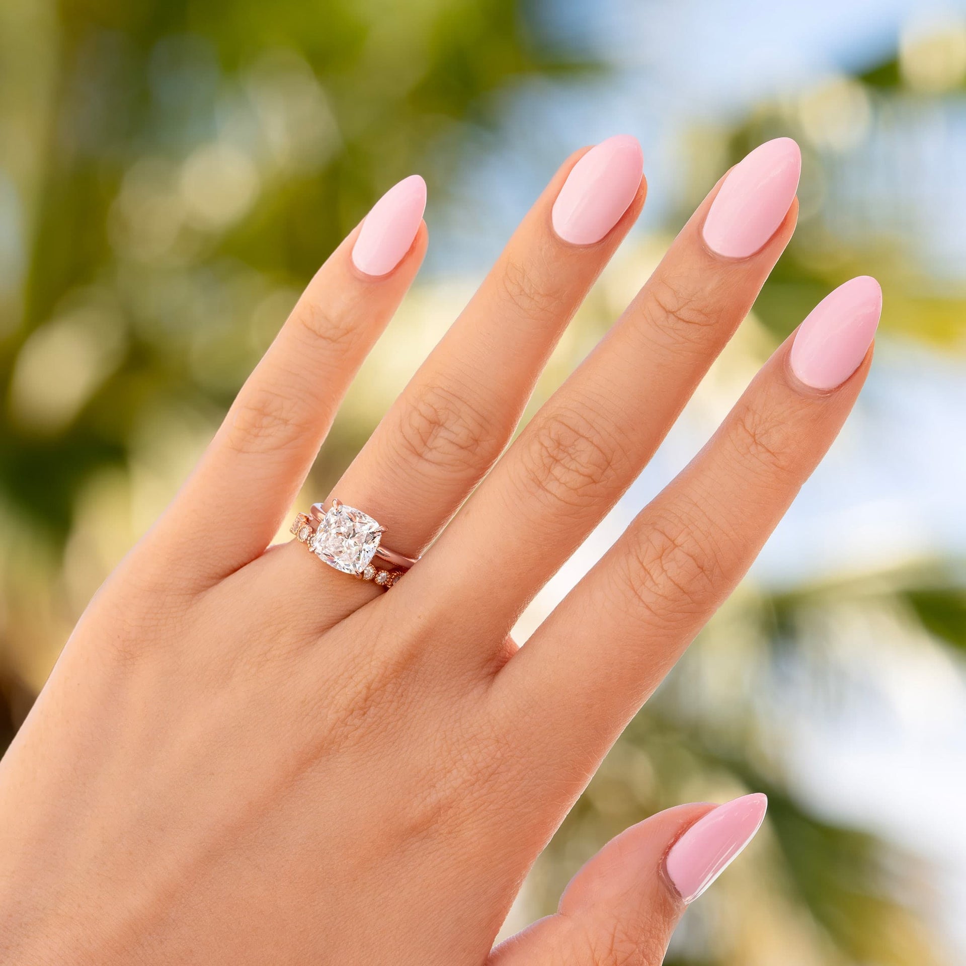 woman wearing rose gold cushion cut engagement ring by palm trees