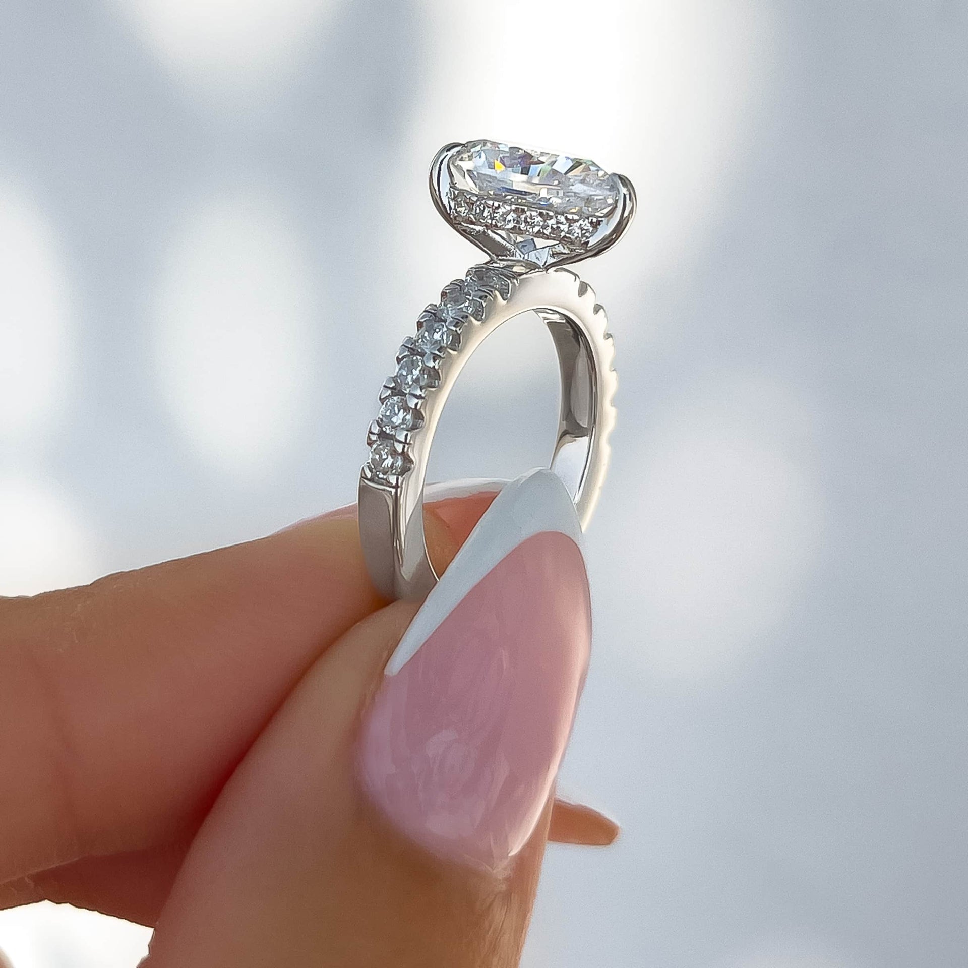 side view of silver pear cut engagement ring with half eternity band and hidden halo