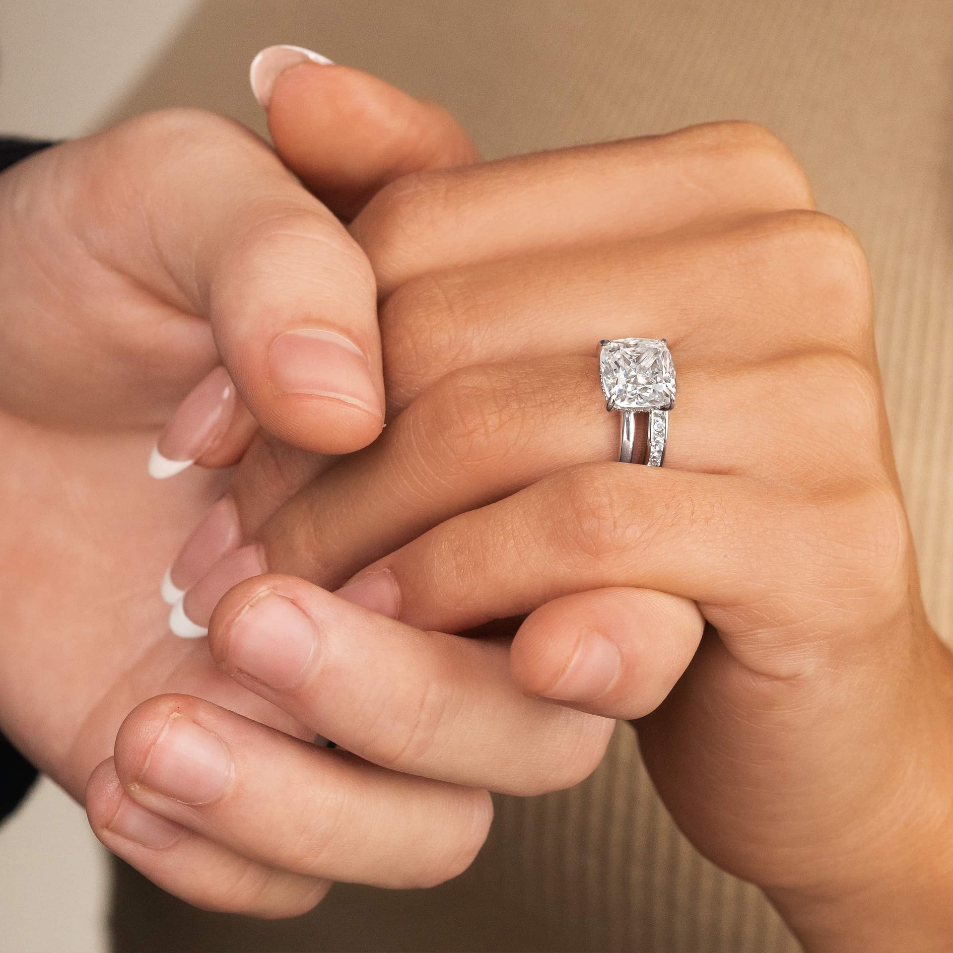 couple holding hands with cushion cut silver engagement ring