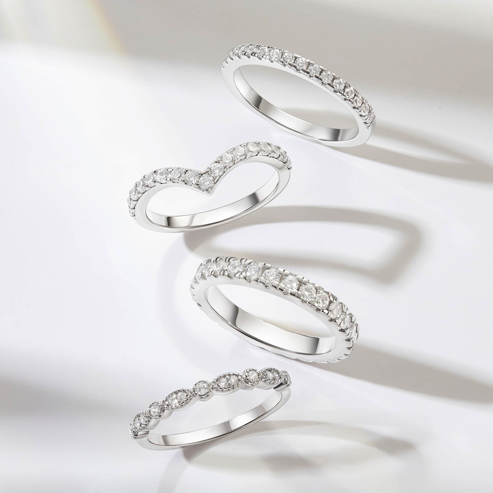 four silver eternity and half eternity wedding bands shown on gray/white background