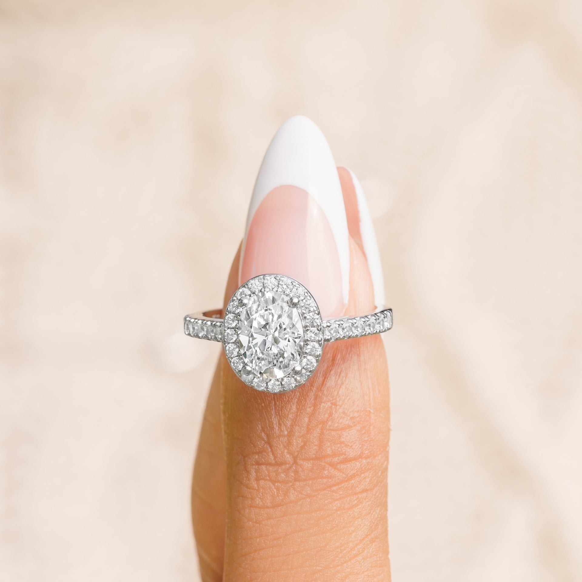 woman pinching oval halo engagement ring