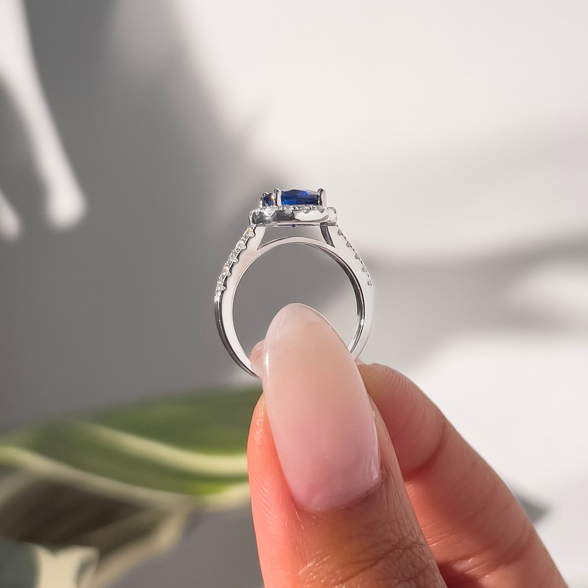 setting shot of round cut tanzanite simulated gemstone engagement ring in female hand with neutral nails