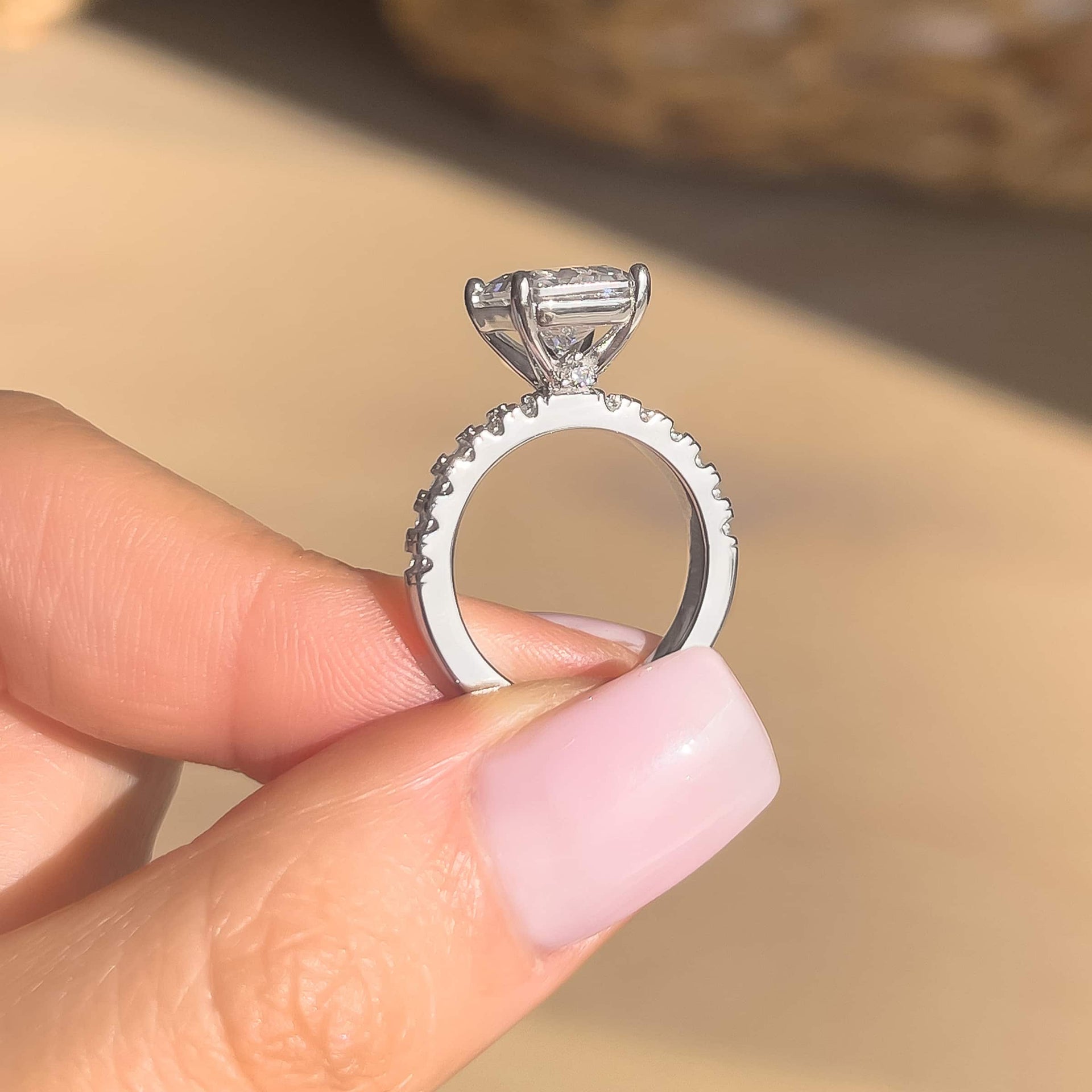 3.75 carat silver engagement ring setting shot shown in silver modeled on female with light pink nails and brown background