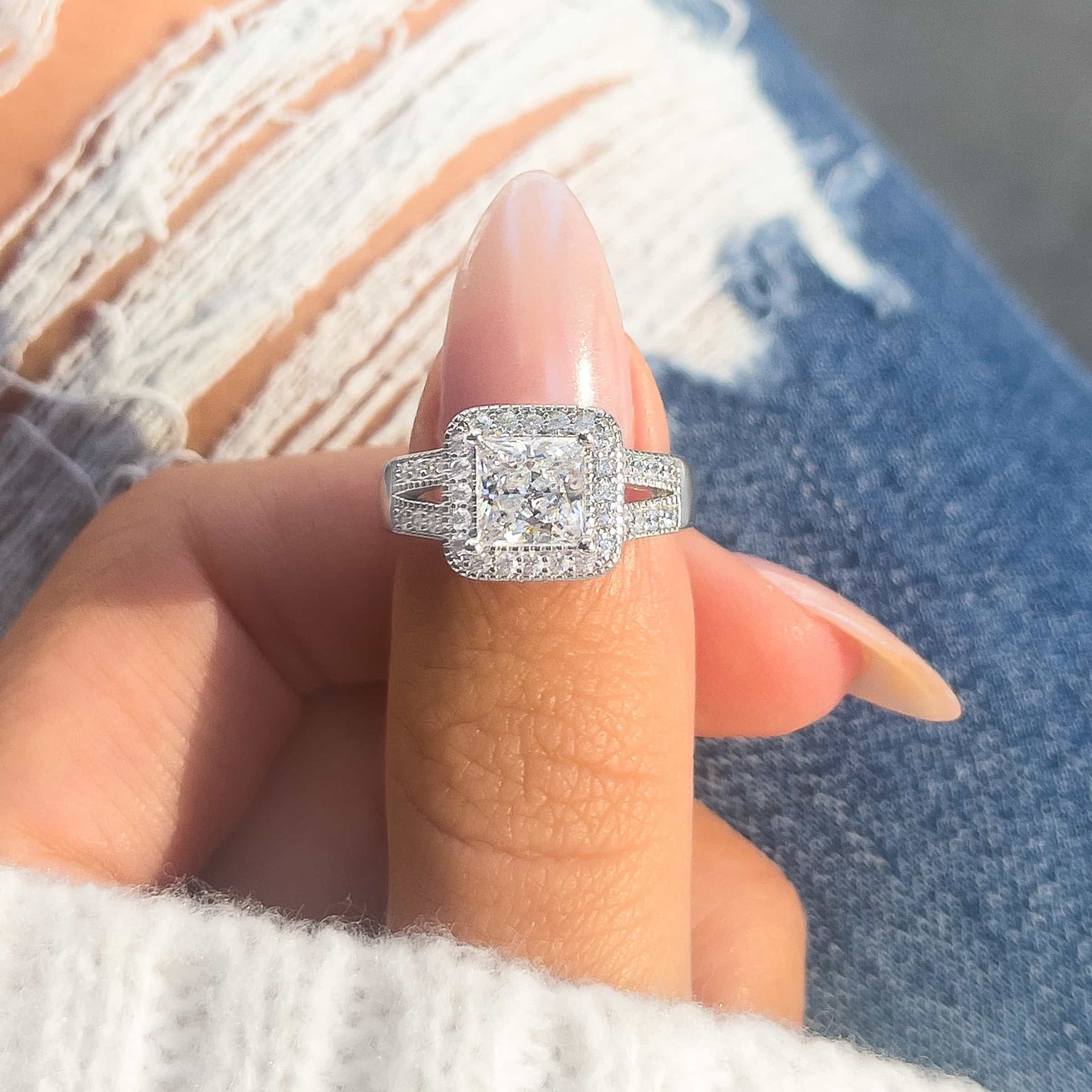 woman pinching princess engagement ring in silver by jeans