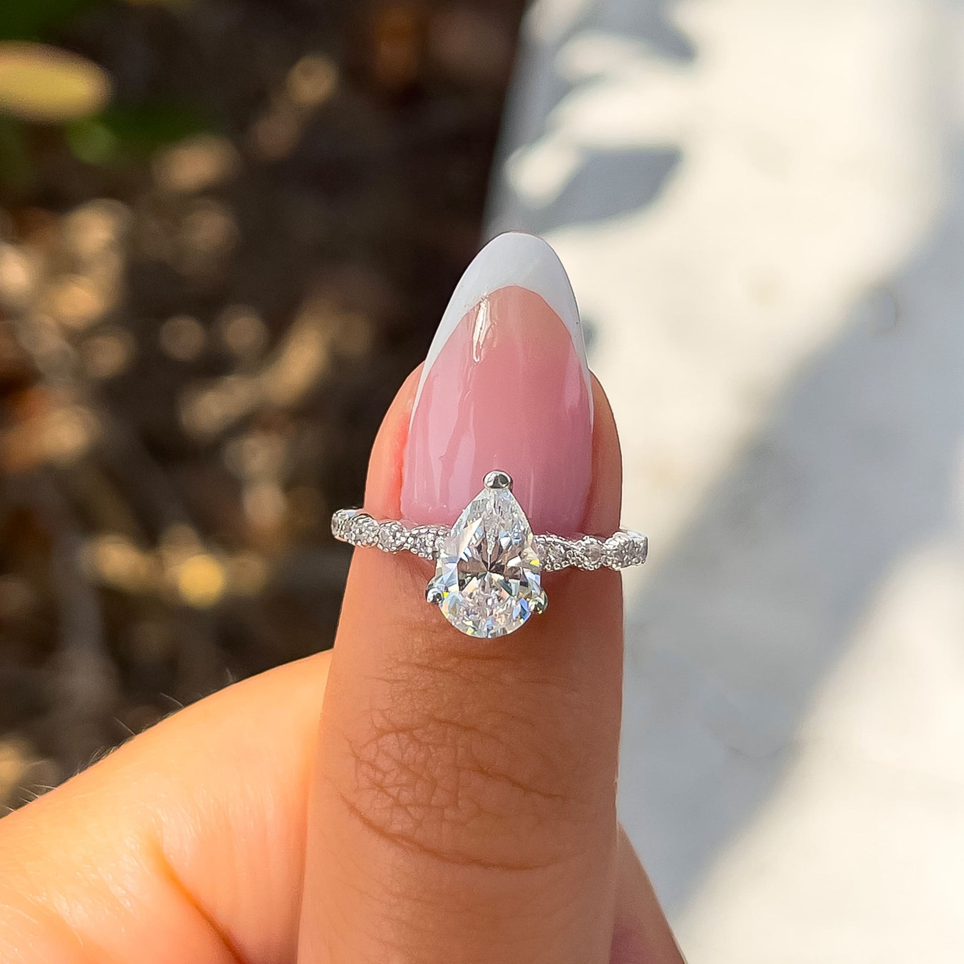 gorgeous vintage style pear cut engagement ring on female hand with french tip nail