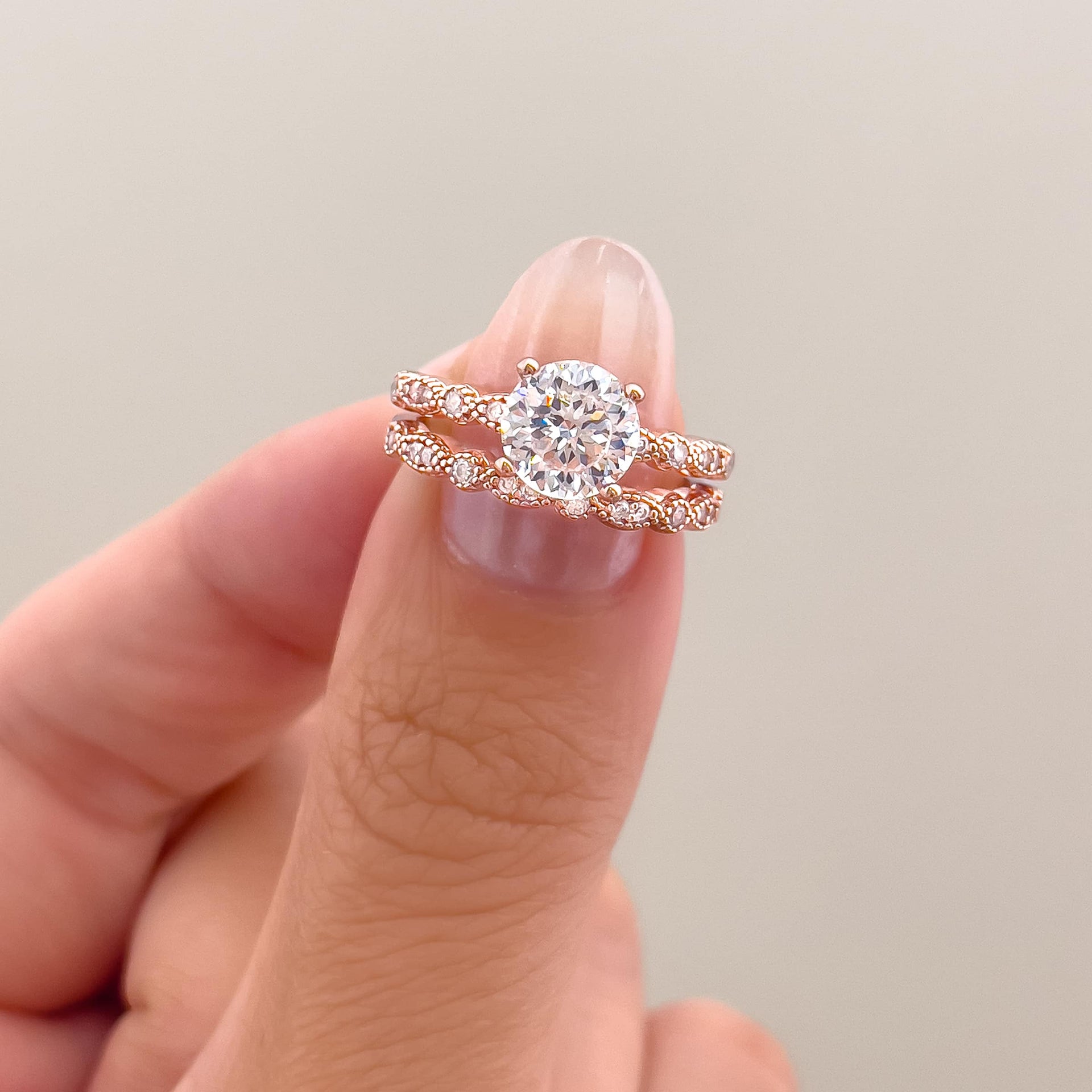 stunning 1.5ct round cut engagement ring in rose gold with vintage detailing and a complimentary wedding band on ladies thumb