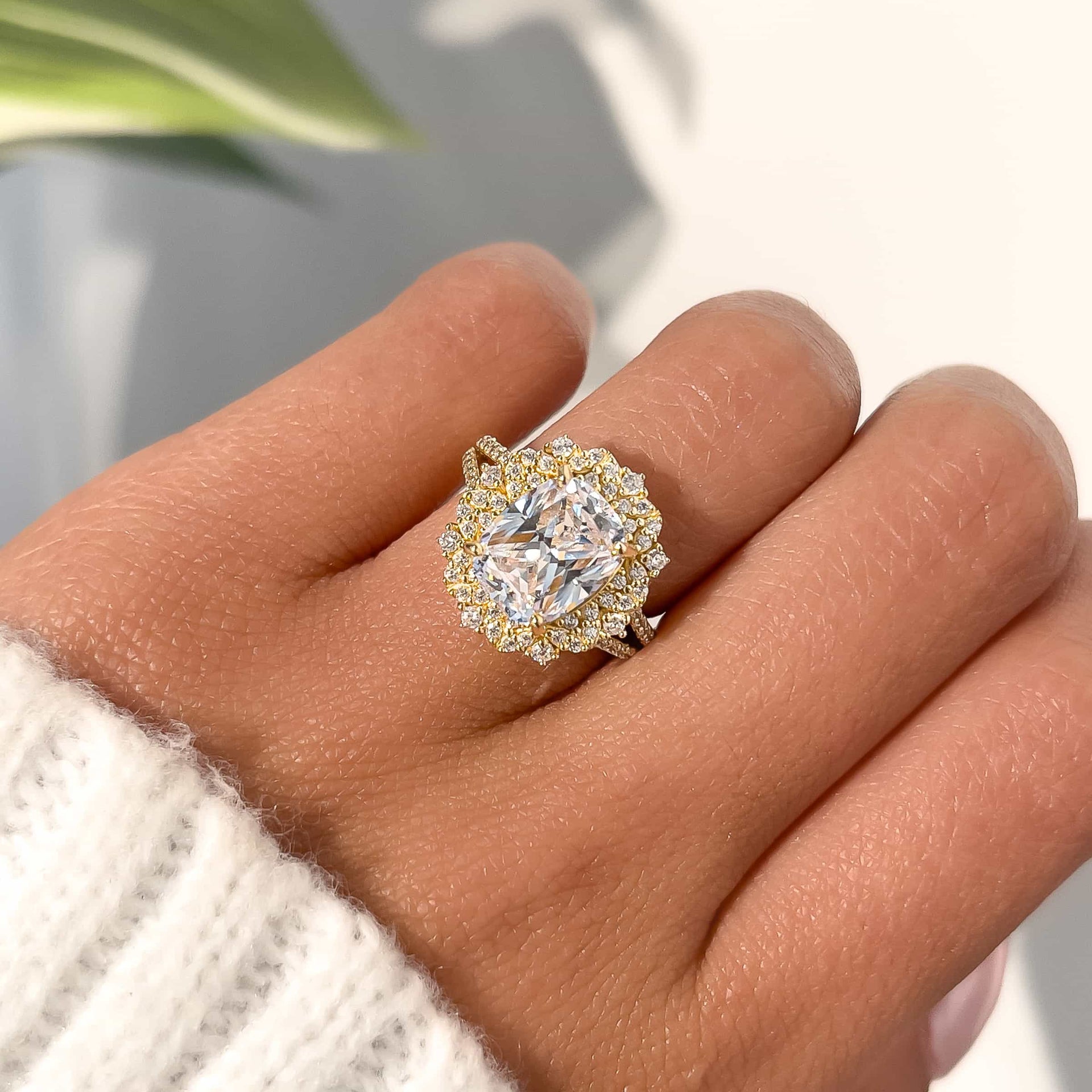 gorgeous gold cushion cut engagement shown on ladies hand with white sweater