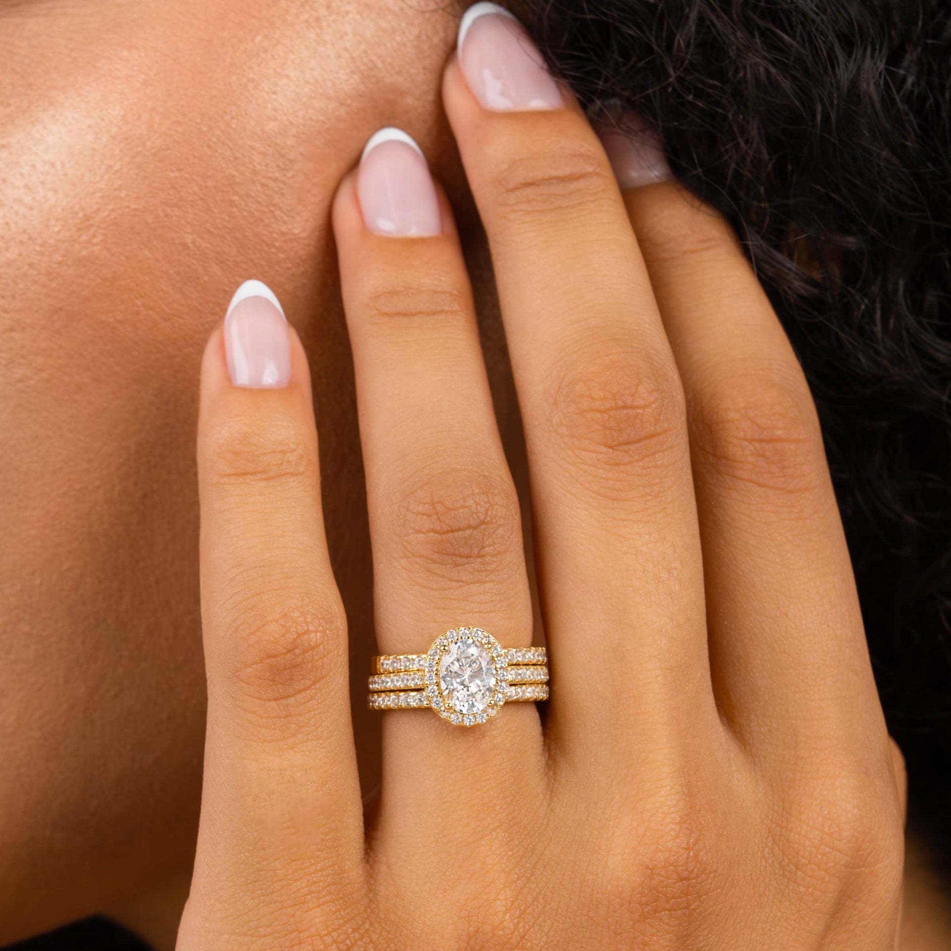 woman wearing gold oval shaped engagement ring with two simple bands