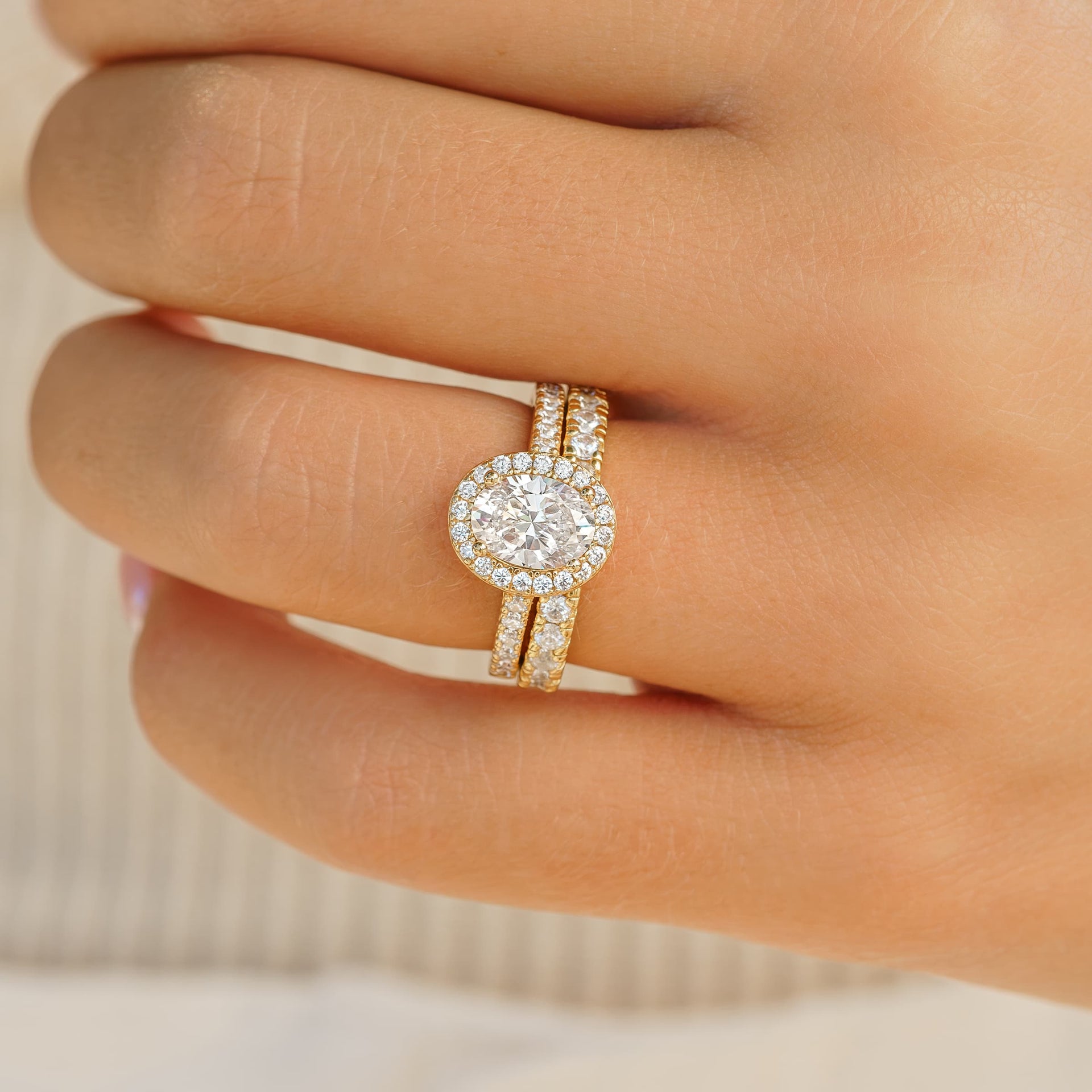 woman wearing halo oval engagement ring with eternity band