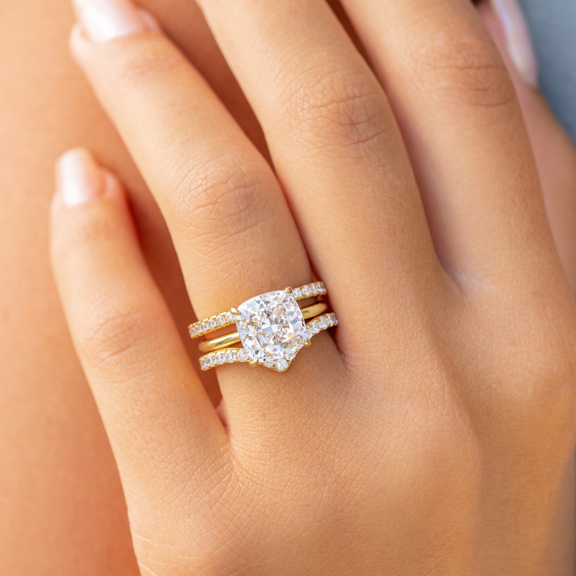 woman wearing cushion cut engagement ring with two wedding bands