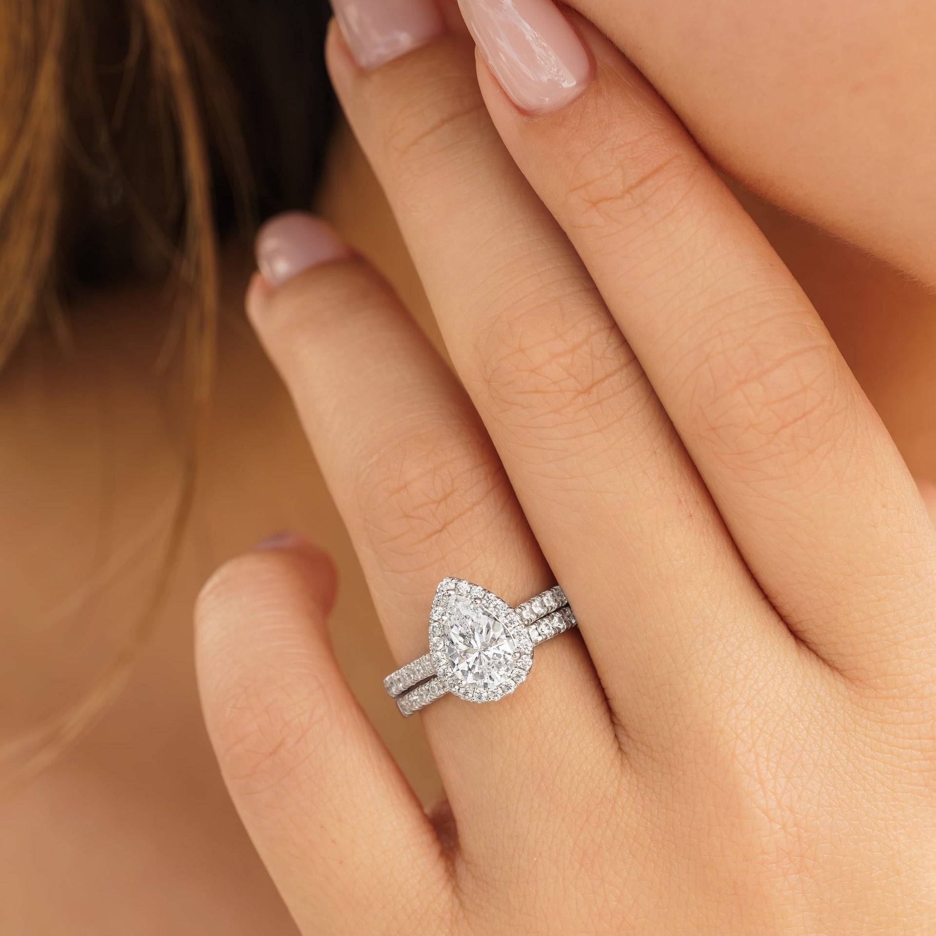 woman wearing silver pear shaped wedding ring set