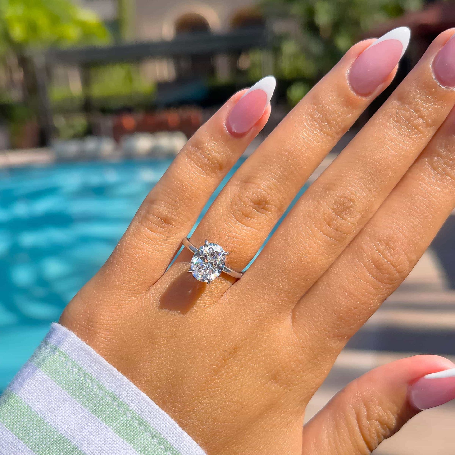 gorgeous silver oval cut engagement ring on woman's hand by pool