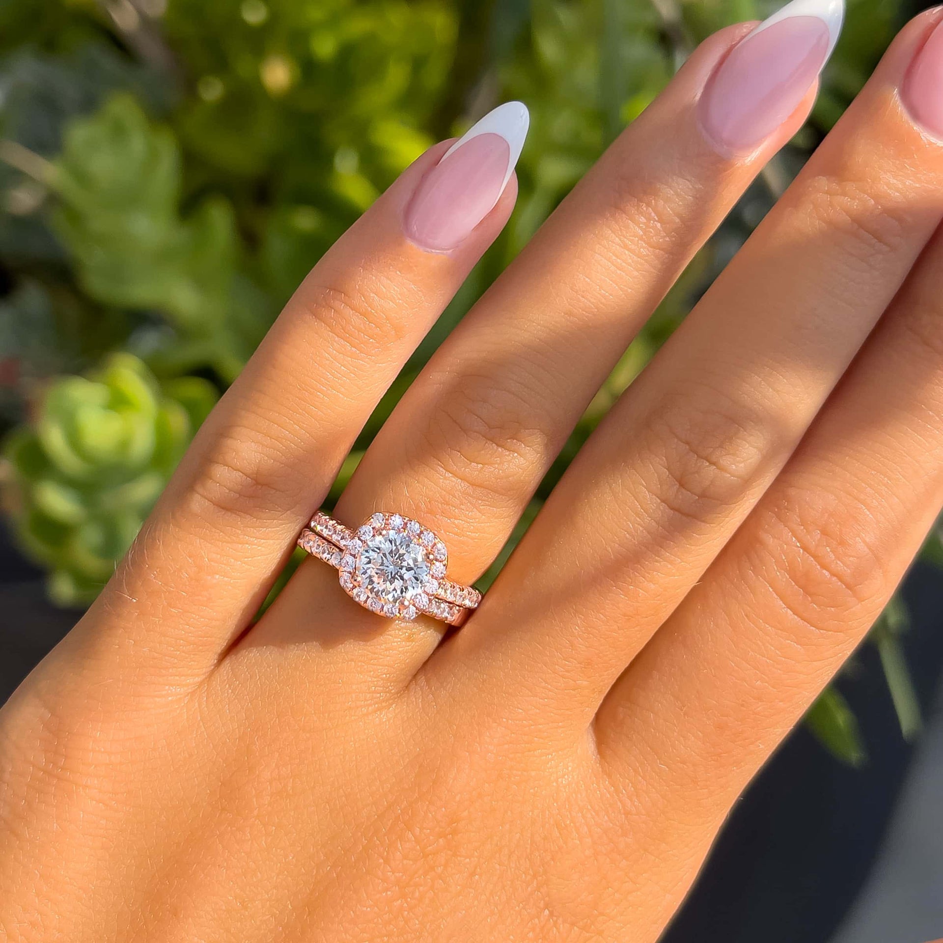 gorgeous engagement ring with a bright and shiny 1.5 ct, round cut center stone set in a halo, and an elegant half-eternity wedding band shown in rose gold