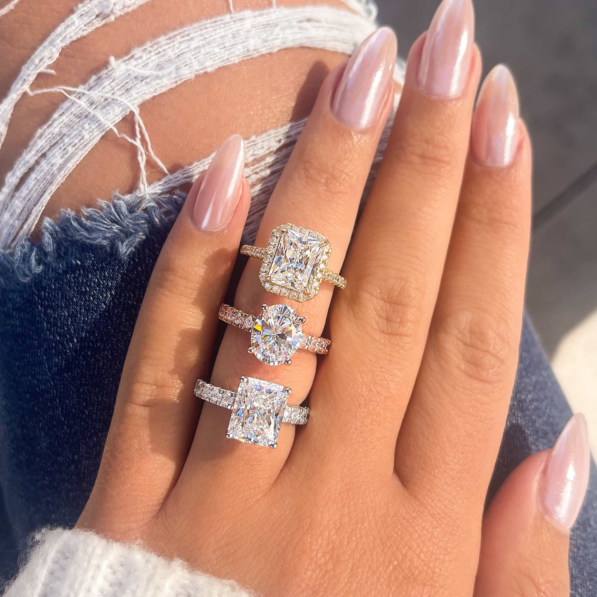 silver kylie engagement ring with two other engagement rings on finger