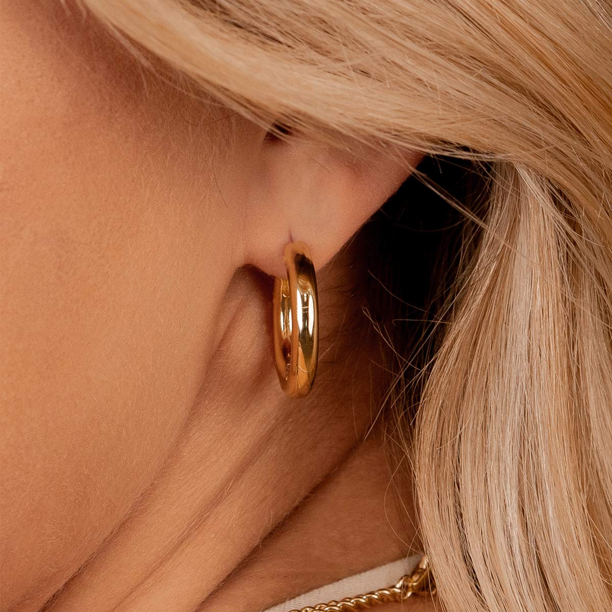 Thick gold plated hoop earrings on model