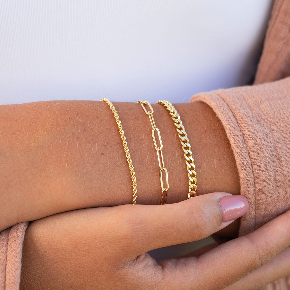 Dainty gold layered bracelets on wrist