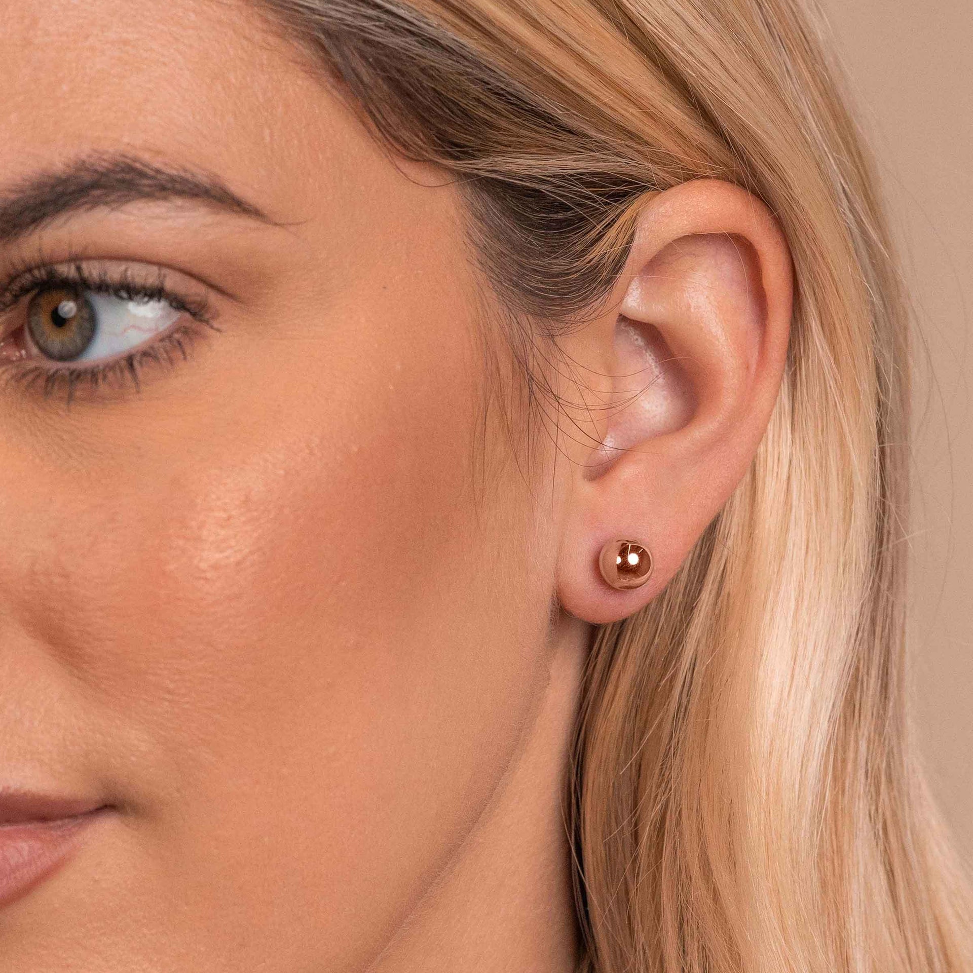Woman wearing rose gold ball stud earrings