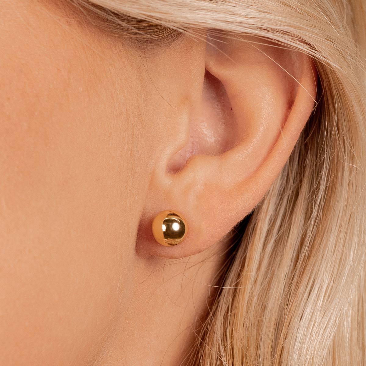 Simple gold ball stud earrings on model