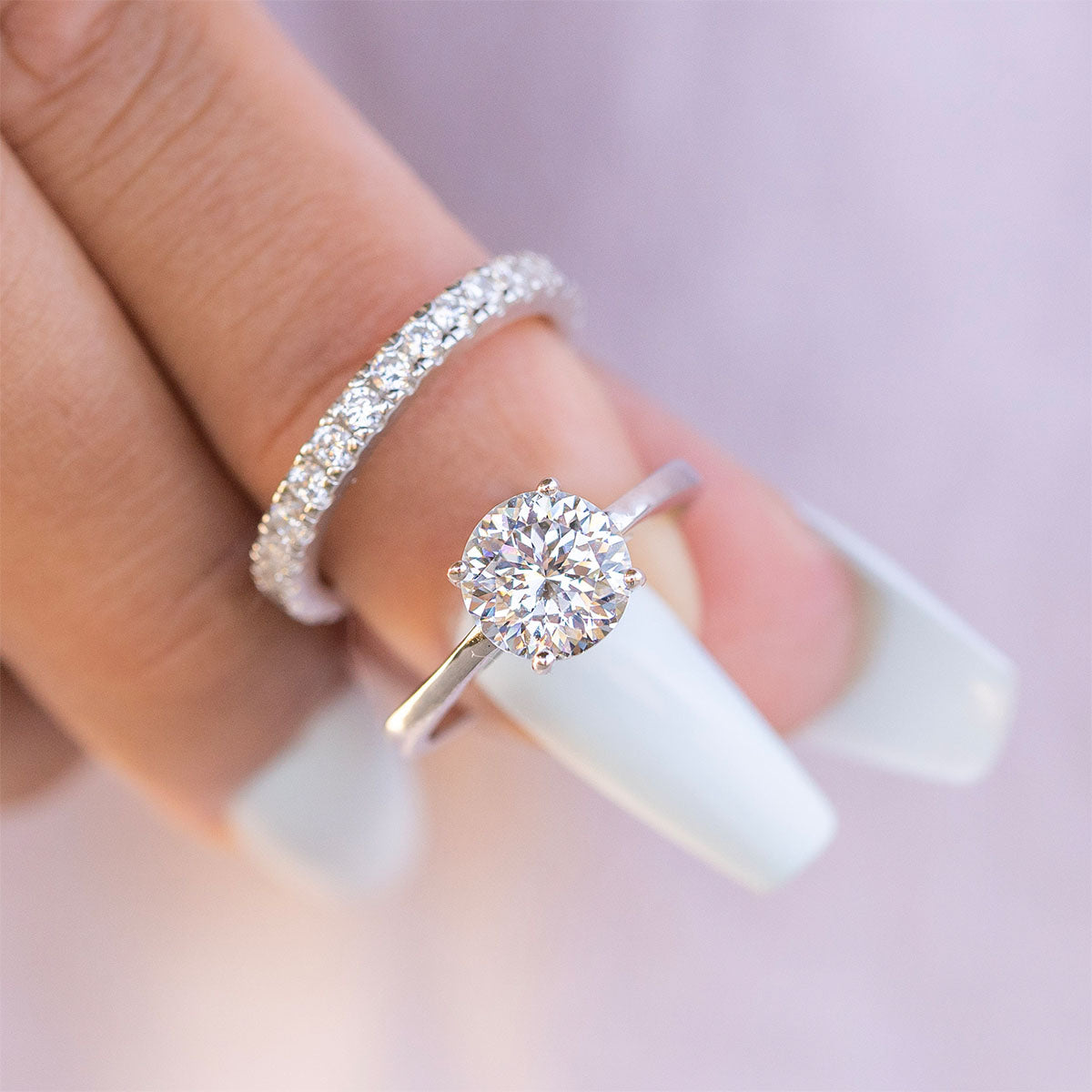 Woman holding round cut engagement ring with band