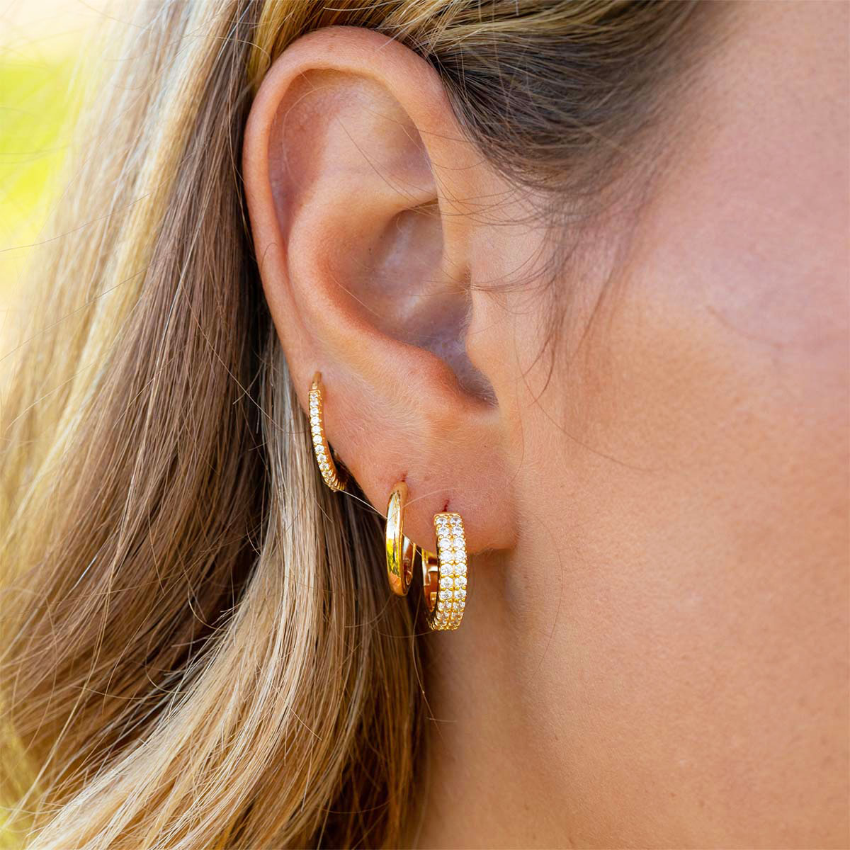Simple gold huggie earrings on model