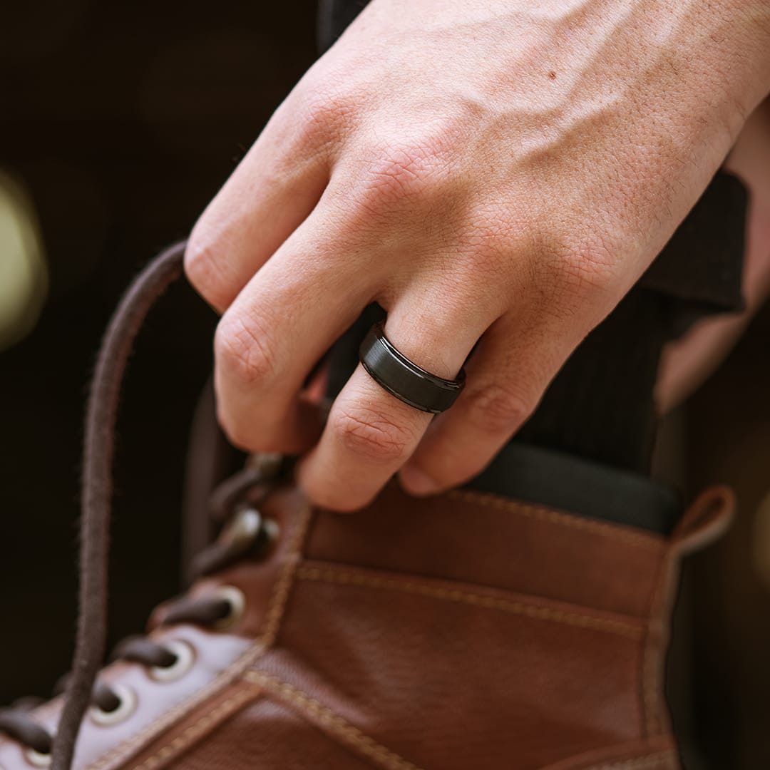 the excalibur black tungsten wedding ring on hand with boot