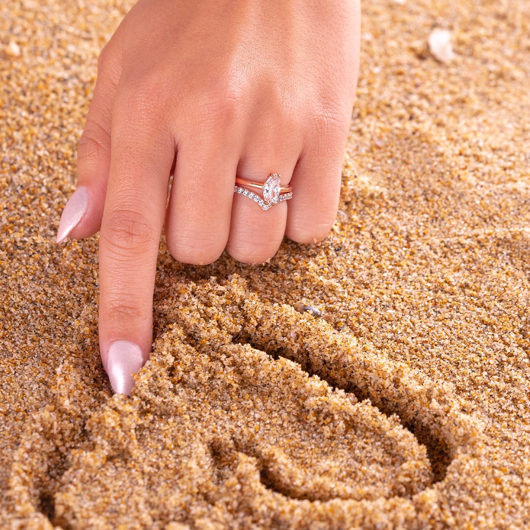 drawing in the sand wearing rose gold wedding rings